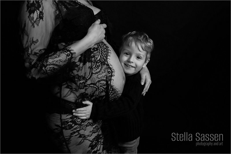 A pregnant woman gracefully posing in a studio maternity shoot, showcasing her baby bump